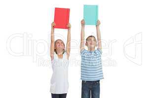 Smiling brother and sister holding their notebooks above their h