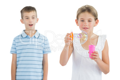 Girl making bubbles while her brother looking at her