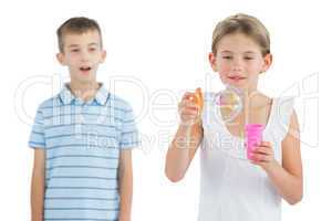 Girl making bubbles while her brother looking at her