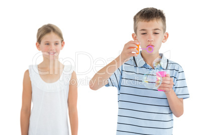 Boy making bubbles while his sister looking at him