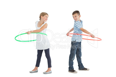 Smiling brother and sister playing with hula hoop