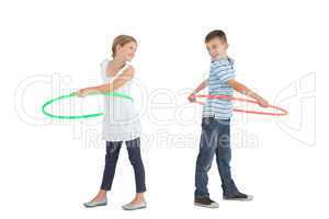 Smiling brother and sister playing with hula hoop