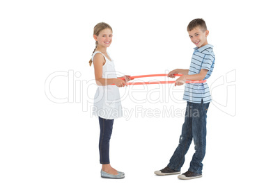 Cheerful brother and sister playing with hula hoop