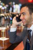 Smiling businessman on the phone having a drink