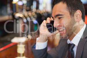 Cheerful handsome businessman on the phone having a drink