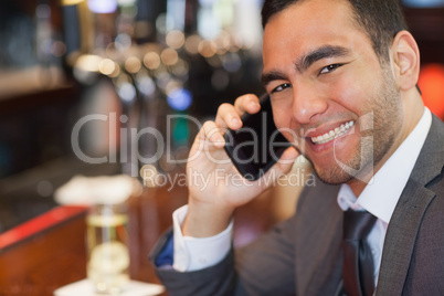 Happy handsome businessman on the phone having a drink