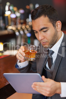 Serious businessman working on his tablet computer while having