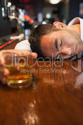 Unconscious businessman holding whiskey lying on a counter