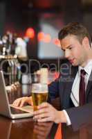 Businessman having a drink while working on his laptop