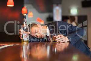 Unmoving businessman holding whiskey glass lying on a counter