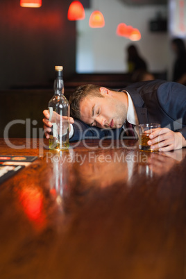 Motionless businessman holding whiskey glass lying on a counter