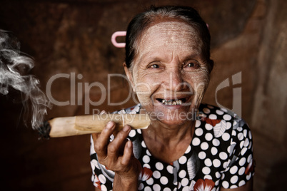 Happy old wrinkled Asian woman smoking