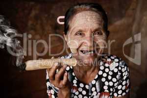 Happy old wrinkled Asian woman smoking