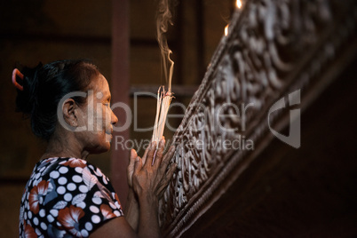 Asian woman praying with incense sticks