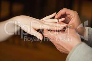 Close up on man putting on ring during marriage proposal