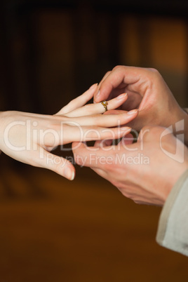 Close up on man putting on ring on his fiances finger during mar