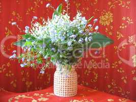 bouquet of lilies of the valley and blue flowers on a red background