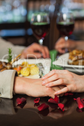 Close up on couple holding hands during dinner