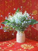 bouquet of lilies of the valley and blue flowers on a red background