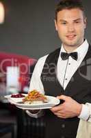 Handsome waiter serving appetizing duck dish