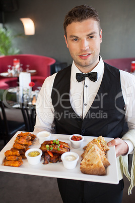 Handsome waiter serving appetizing finger food platter
