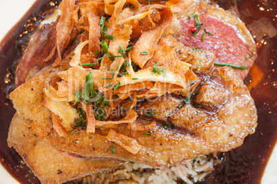 Close up of crispy duck on bed of rice with gravy