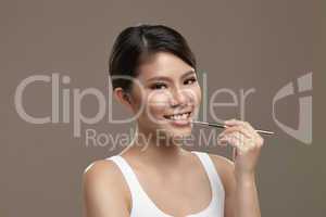 female asian applying lipgloss