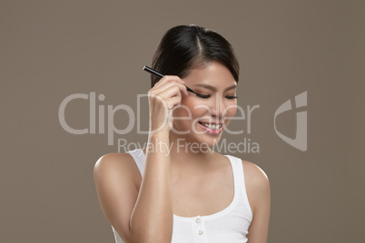 female asian applying eye liner