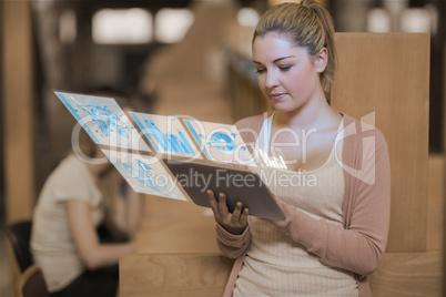 Pretty blonde student working on her futuristic tablet