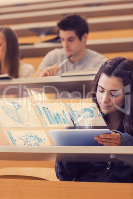 Pretty student analysing graphs on her digital tablet computer