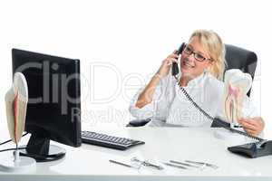 Zahnärztin telefoniert am Schreibtisch