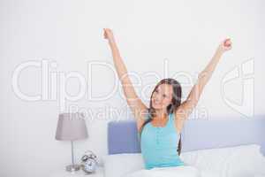 Brunette woman stretching her arms in bed in the morning