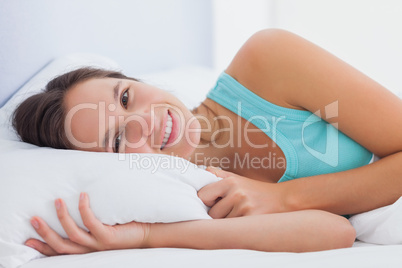Woman lying in bed with eyes open and smiling