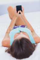 Woman laying on her bed with her mobile phone