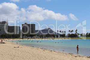 Sandstrand auf Hawaii bei Honolulu mit klarem blauen Meer und Personen im Wasser