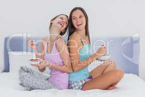 Two girls in bed eating cereal