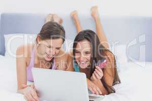 Friends shopping online on bed