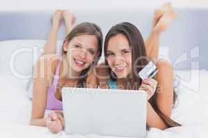 Friends shopping online on bed using laptop