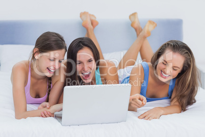 Friends lying on bed with laptop