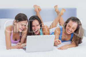 Friends lying on bed with laptop