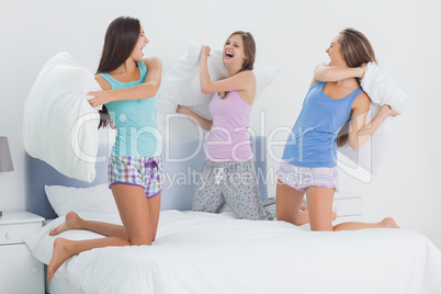 Girls in bed having pillow fight in pajamas