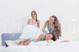 Happy girls having fun at slumber party in bed