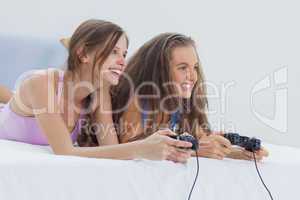 Excited girls playing video games on bed