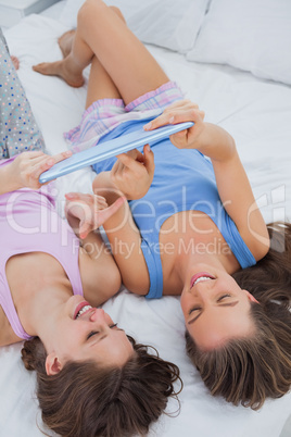 Girls lying in bed with tablet