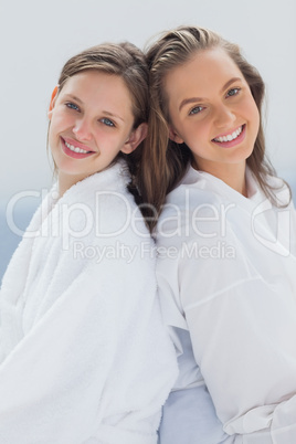 Friends wearing bathrobe sitting on bed