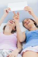 Girls lying in bed holding tablet