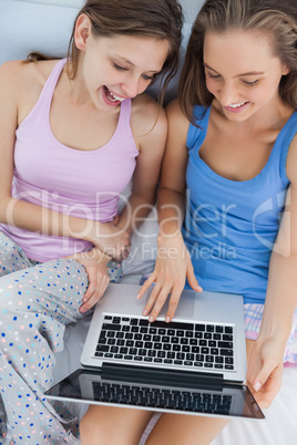 Girls sitting on bed using laptop