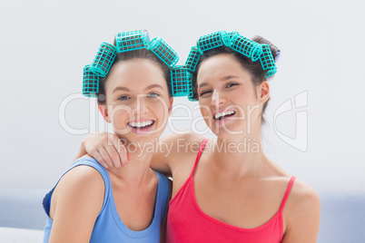 Girls in hair rollers and pajamas smiling at camera