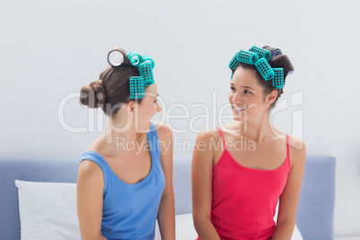 Girls wearing hair rollers sitting in bed