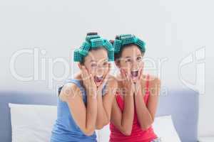 Friends with hair rollers on sitting in bed